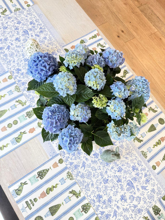 Bouquet of blue hydrangeas on a decorative table runner with a wooden surface.